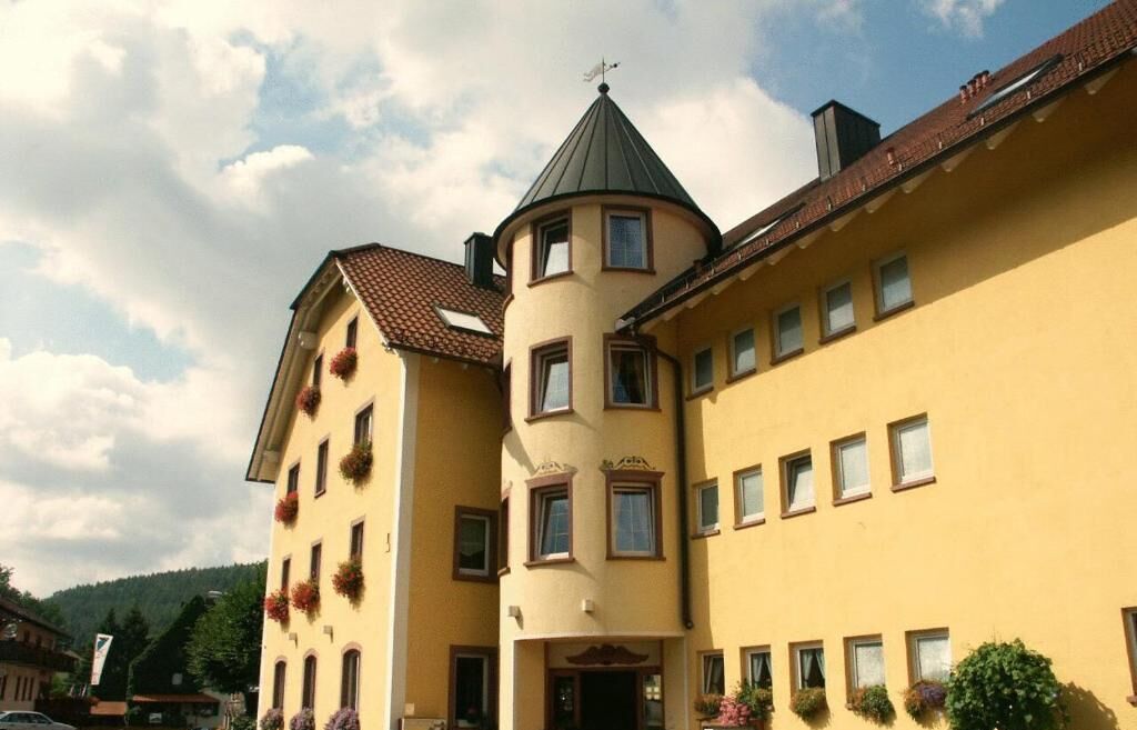 A multi-story building with a central tower and a flat-roofed annex.