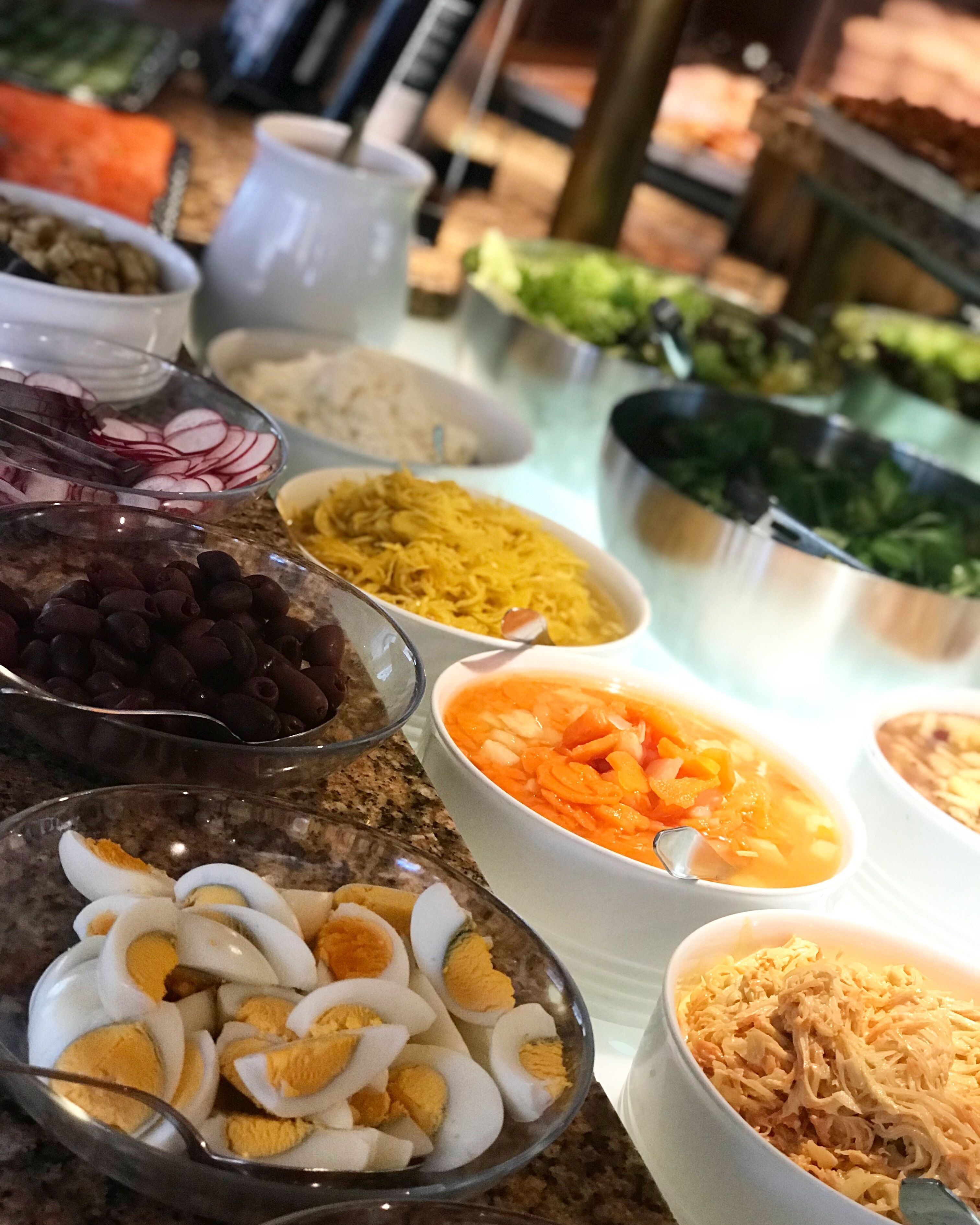 A buffet table with various food items including sliced radishes, shredded carrots, boiled eggs, and shredded chicken.