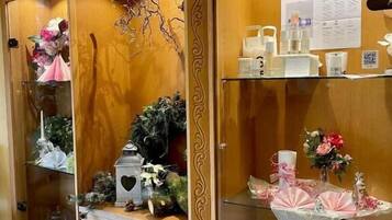 Un aparador de madera con puertas de cristal, que contiene diversos objetos como flores, velas y adornos decorativos.