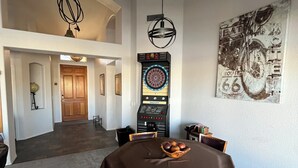 A dining area with a round table, chairs, and a dartboard.