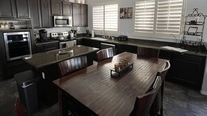 A modern kitchen with dark cabinetry, a central island, and a ceiling fan.
