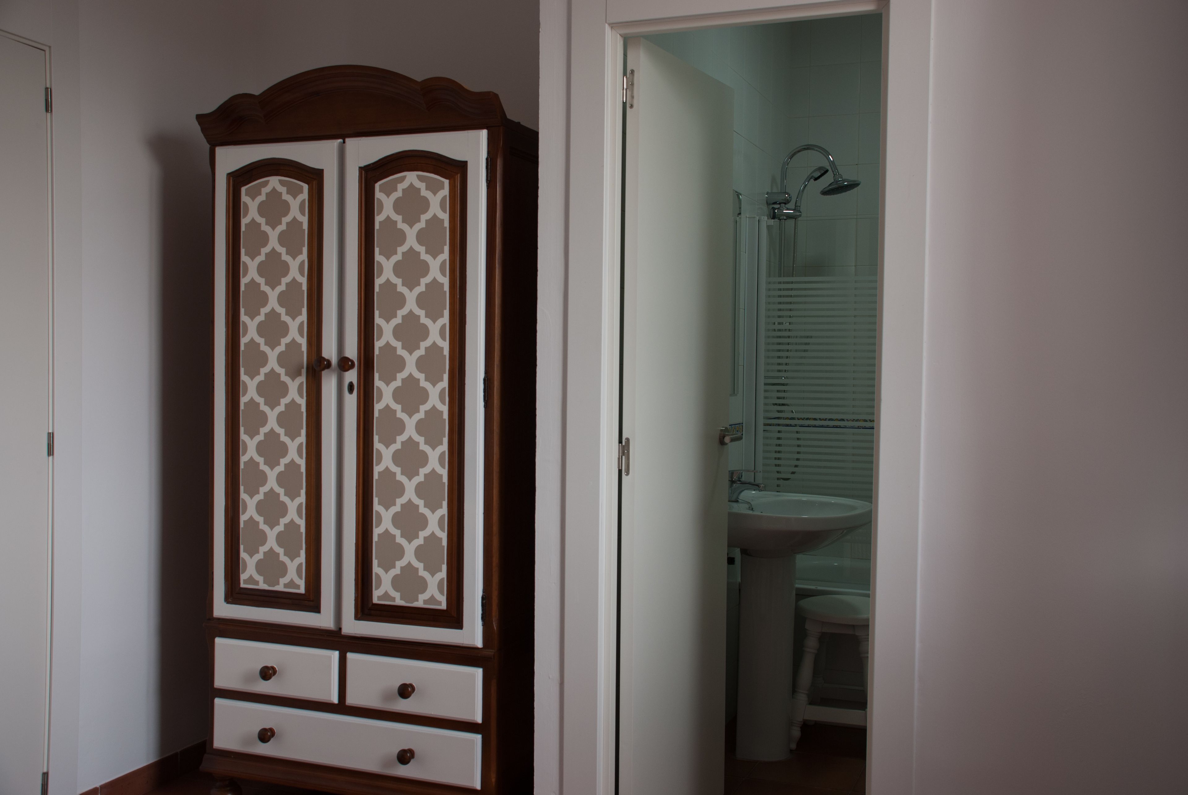 Una habitación con armario y baño que incluye lavamanos y ducha.