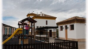 Un parque infantil con un tobogán amarillo y un niño jugando.