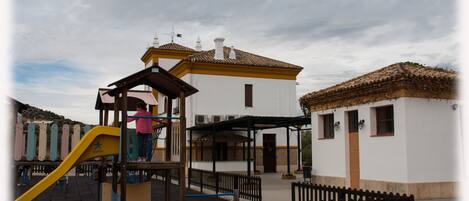 A playground with a yellow slide and a child playing.