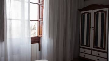 Una habitación con cama, ventana con cortinas y armario.