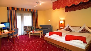 A hotel room with a bed, a sofa, a desk with a computer, a chair, and a TV.