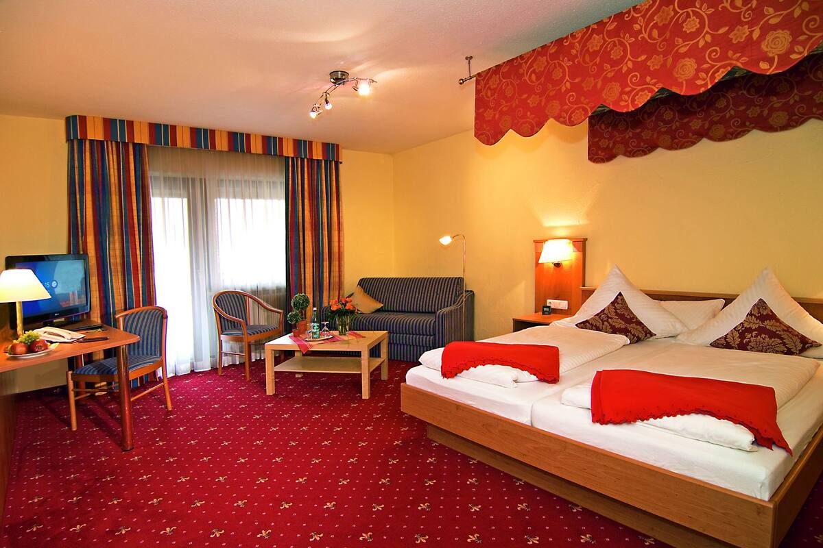 Une chambre d’hôtel comprenant un lit, un canapé, un bureau avec un ordinateur, une chaise et un téléviseur.