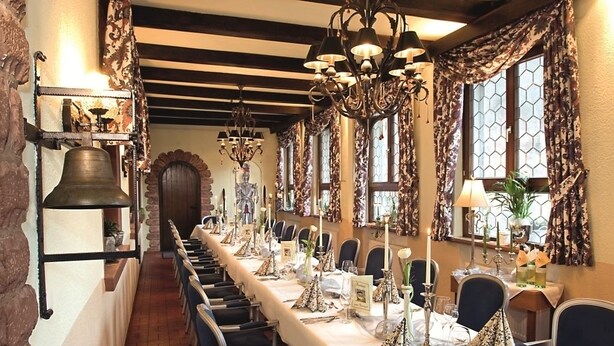 A long dining table set with chairs, candles, and a chandelier.