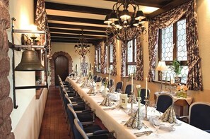 Una larga mesa de comedor dispuesta con sillas, velas y un candelabro.