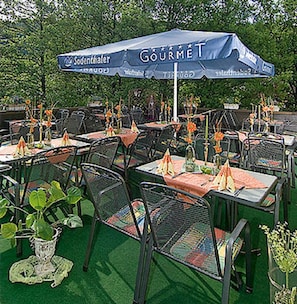 An outdoor dining area with tables and chairs, an umbrella with 'GOURMET' branding, and a 'Sodenthaler' sign. - Gasthof Zum Spessart (Mespelbrunn)