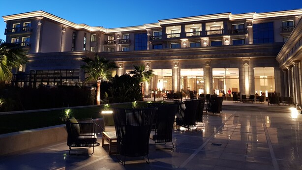 Um hotel com um pátio externo amplo, vários níveis e uma entrada bem iluminada.