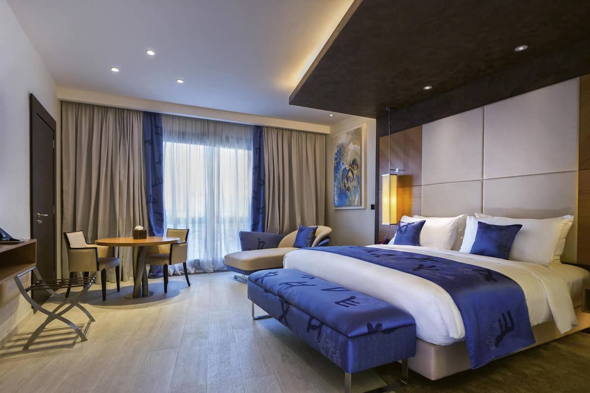 Une chambre d’hôtel moderne, dotée d’un grand lit, d’un bureau et d’une chaise.