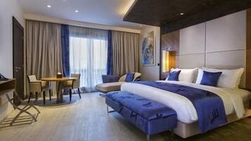 A modern hotel room with a large bed, a desk, and a chair.