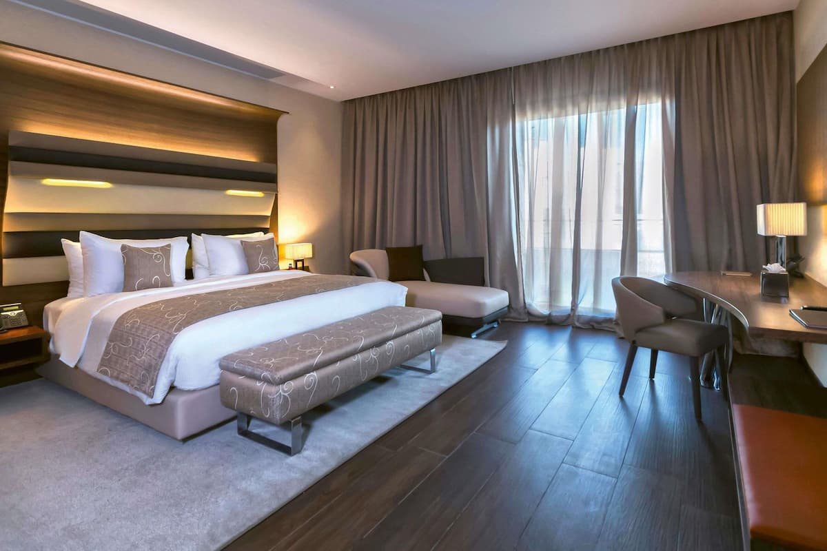 Ein modernes Hotelzimmer mit einem großen Bett, einem Schreibtisch, einem Sessel und einer Couch.