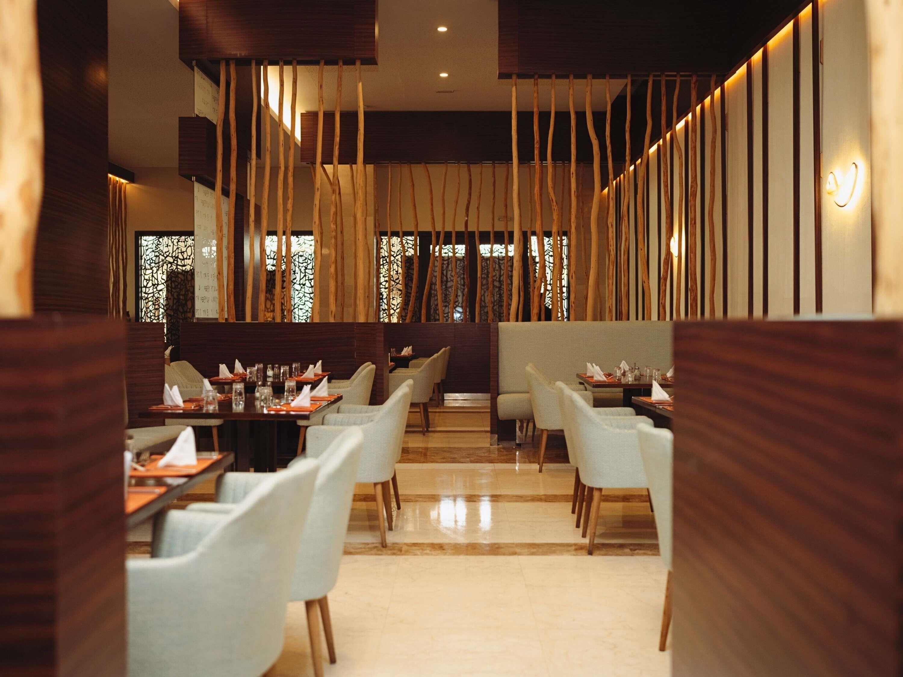 A restaurant interior with wooden slats, tables, and chairs.