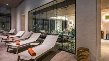 Een binnenzwembad, ligstoelen bij het zwembad