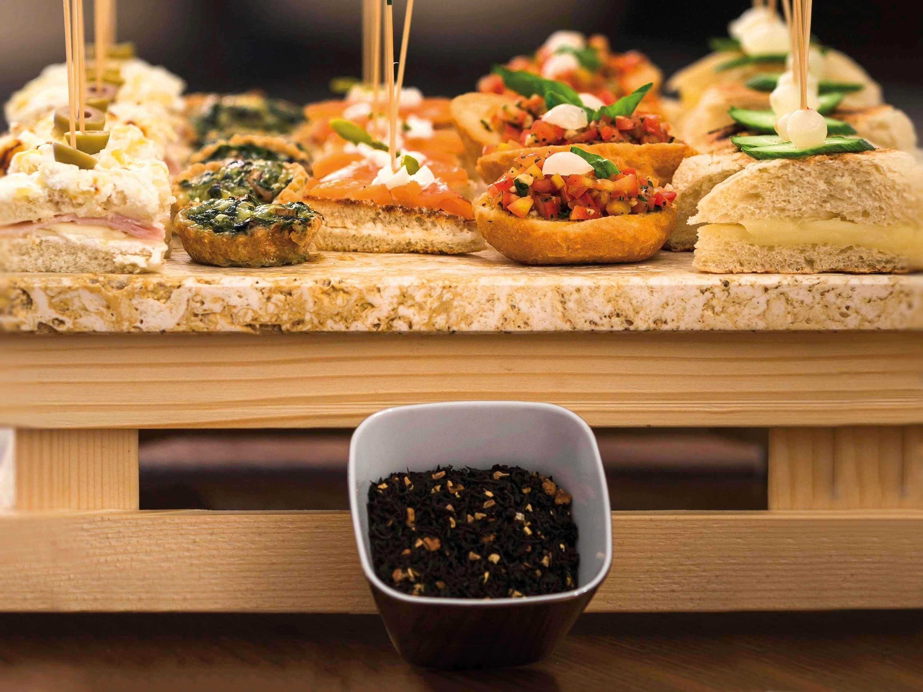A variety of appetizers on a marble board, including items with olives, smoked salmon, and a bowl of black pepper.