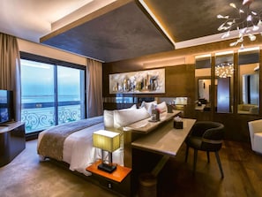 A hotel room with a bed, bedside table, lamp, chair, and a large window with a view. - Mövenpick Hotel du Lac Tunis (Tunis)