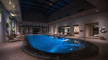 Una piscina techada, sillones reclinables de piscina