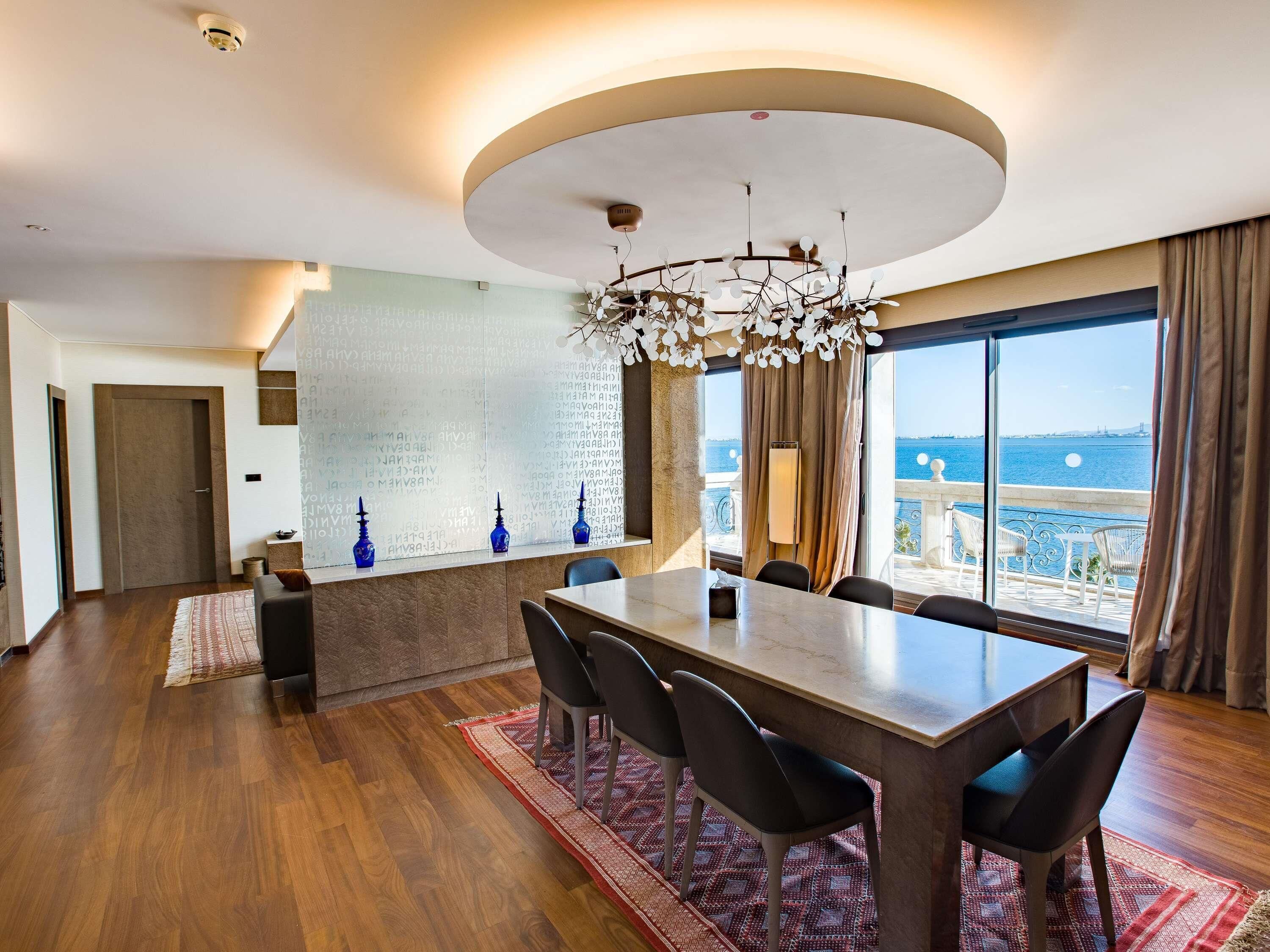 Un espace repas moderne avec une grande table, des chaises et une vue sur la mer.