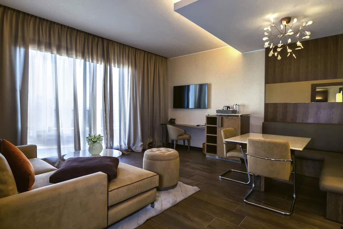 A modern living room with a sofa, ottoman, and a dining area with a table and chairs.