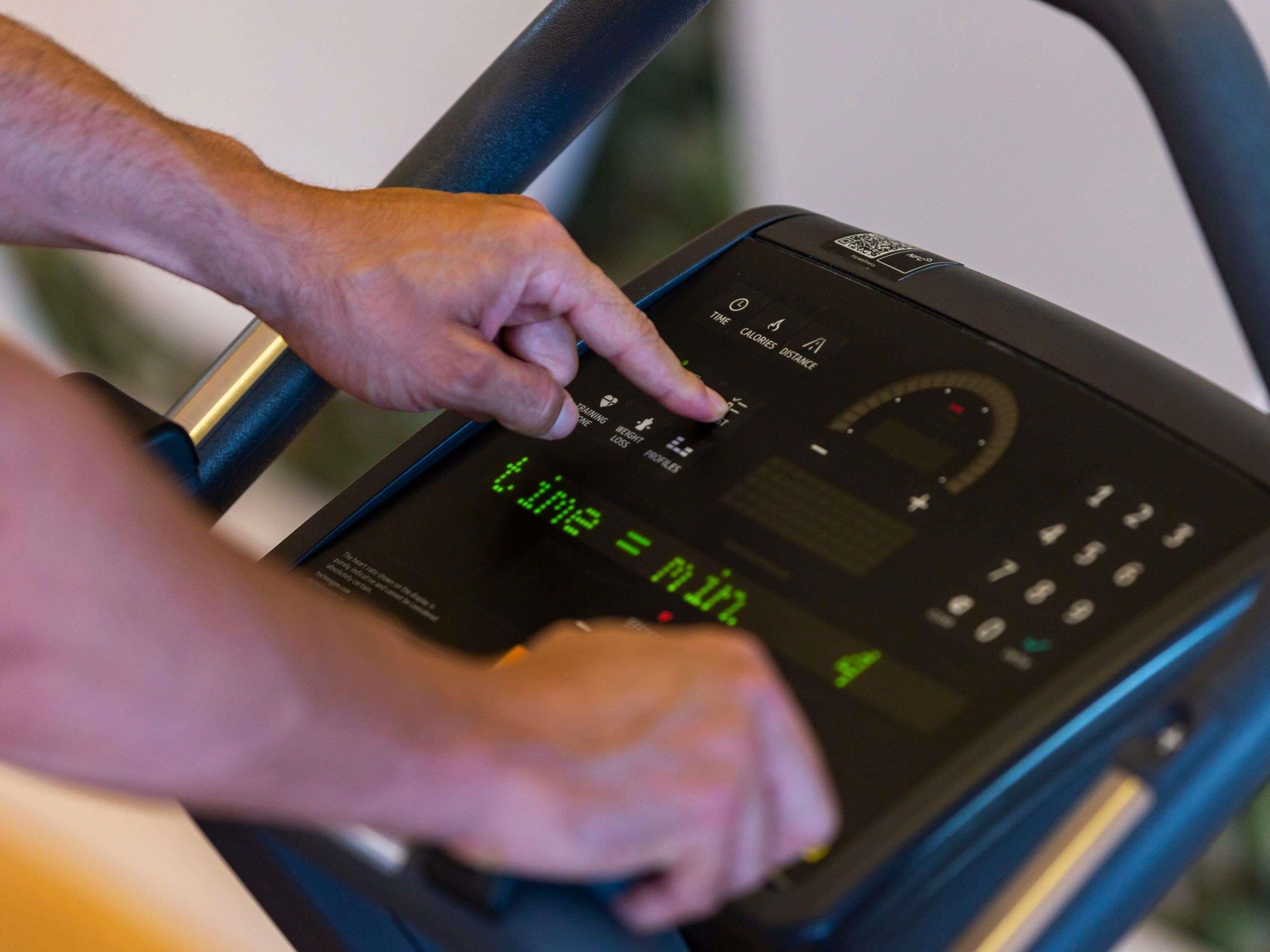 A person using a treadmill with a digital display showing time and other metrics.