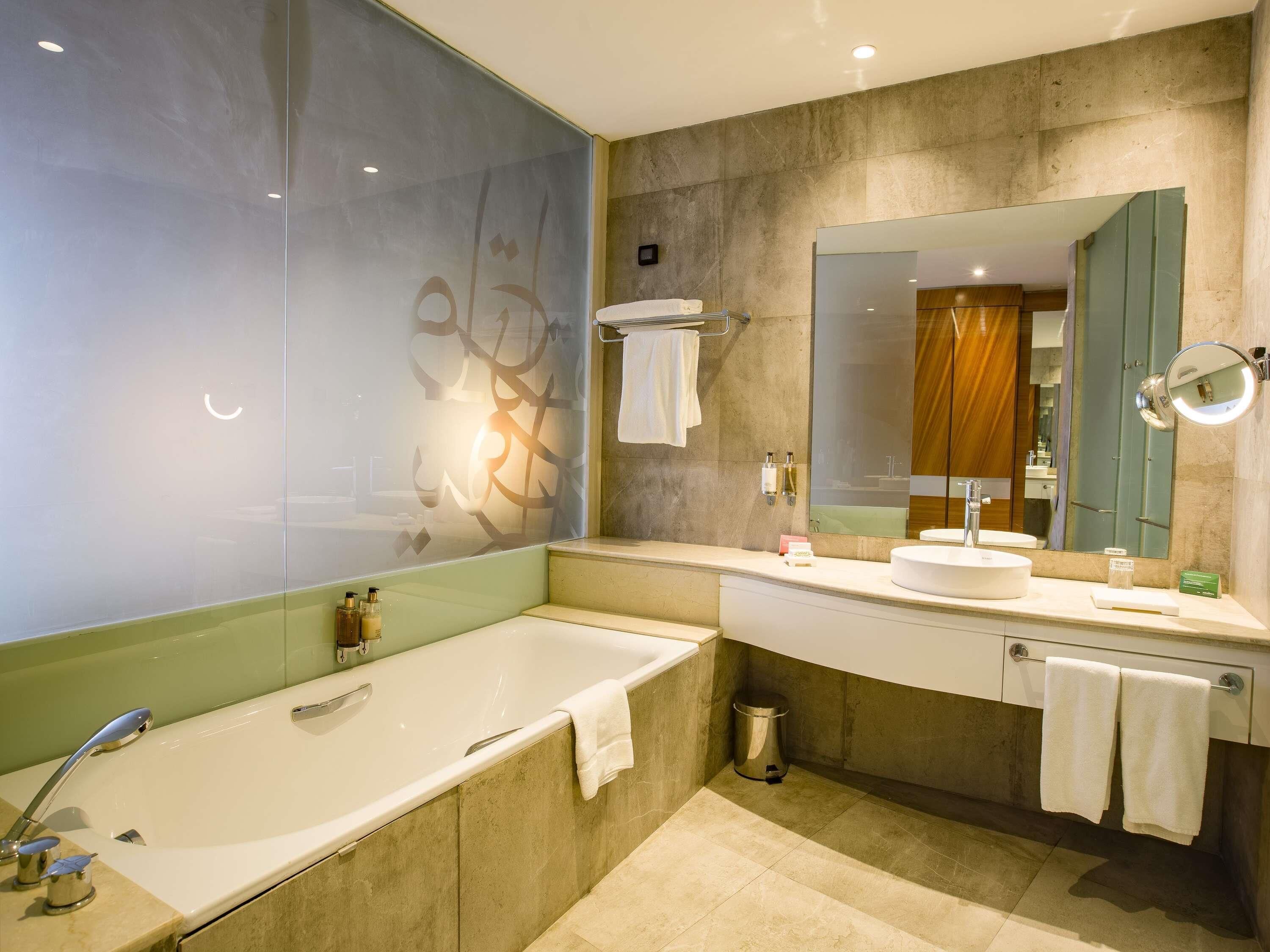 A modern bathroom with a bathtub, a sink, a mirror, and a towel rack.