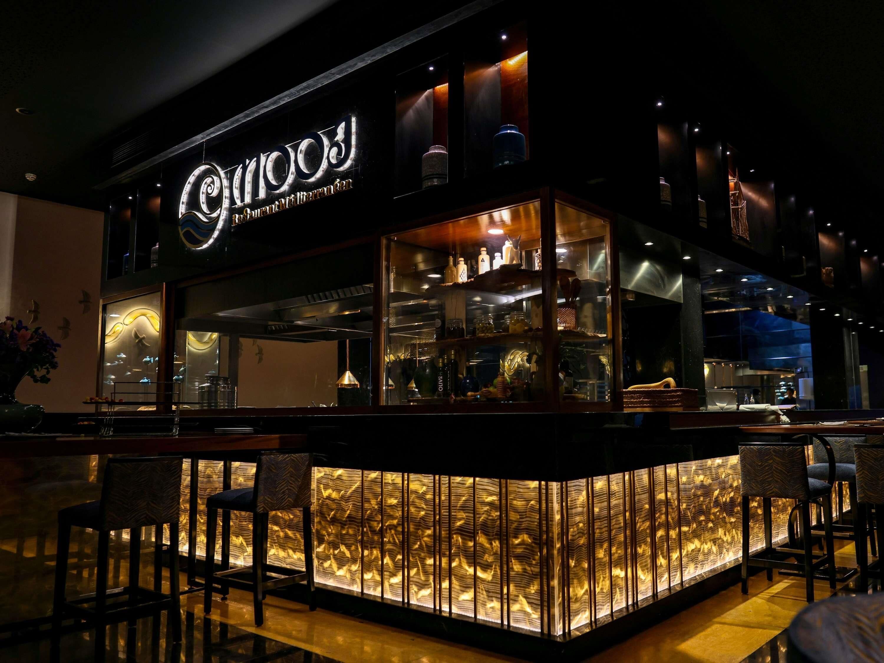 Un bar con diseño moderno, que cuenta con un cerramiento de vidrio y zona de estar.