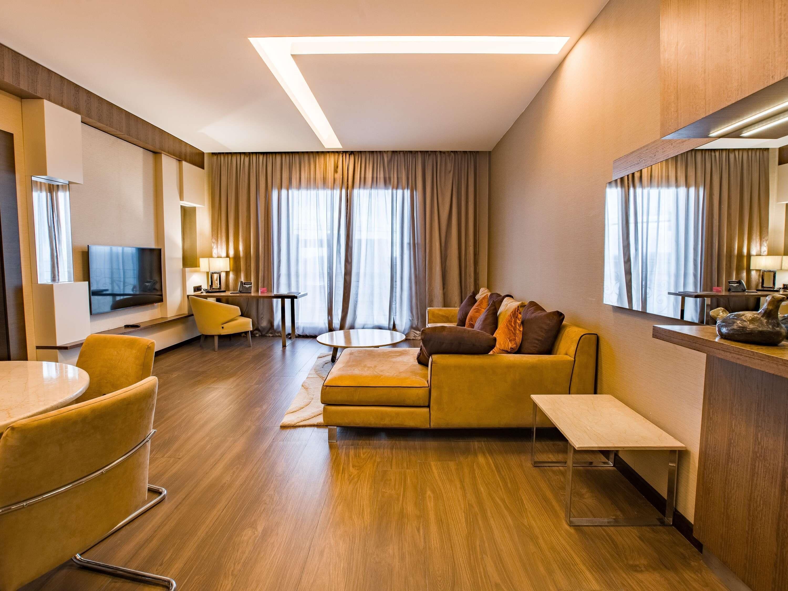 Een hotelkamer met een bank, een televisie, een bureau en een eethoek.