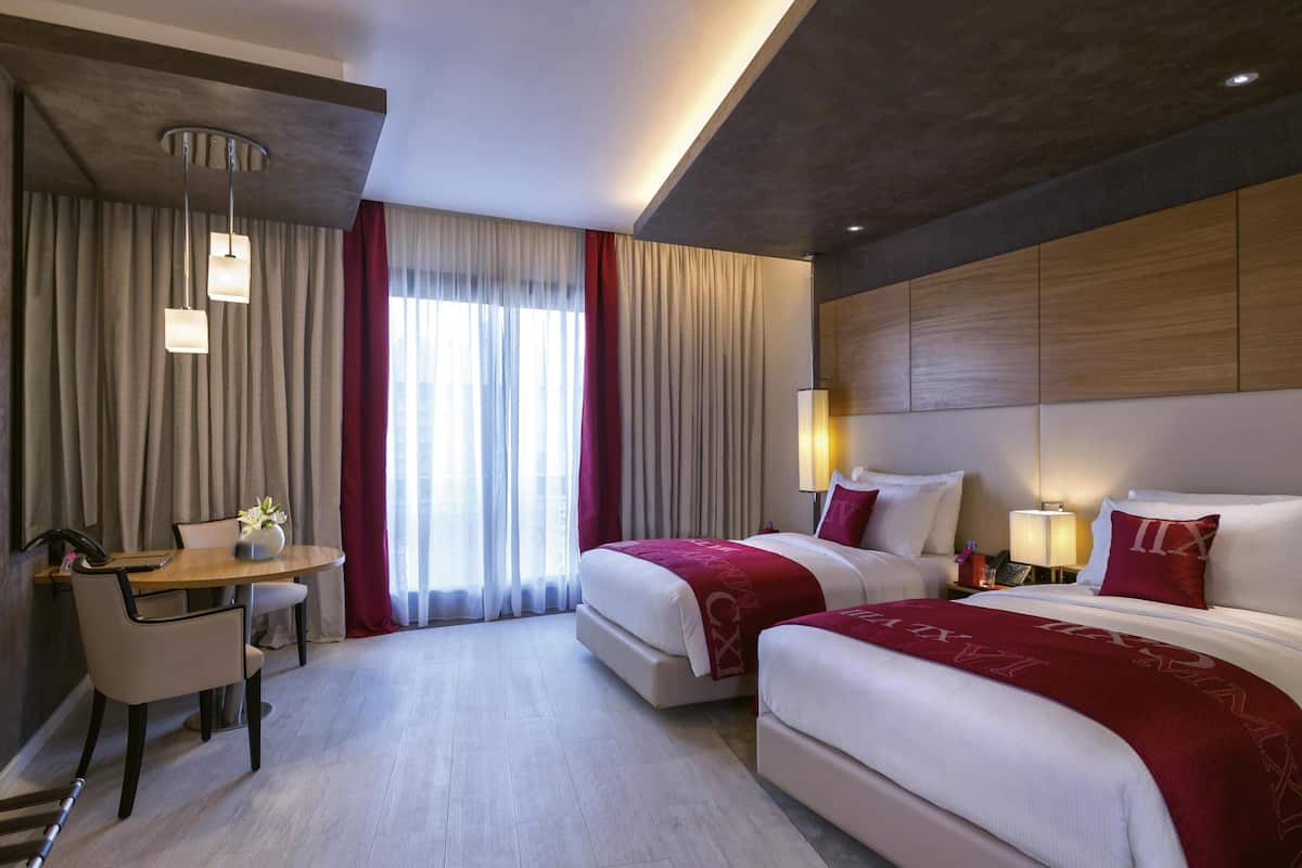 Une chambre d’hôtel avec deux lits, un bureau et une chaise.