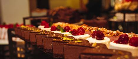 Una exhibición de postres con diversas opciones de chocolate y crema, algunas coronadas con frambuesas.