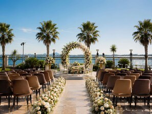 An outdoor wedding ceremony setup with chairs arranged in rows, a floral arch, and a view of the sea. - Mövenpick Hotel du Lac Tunis (Tunis)