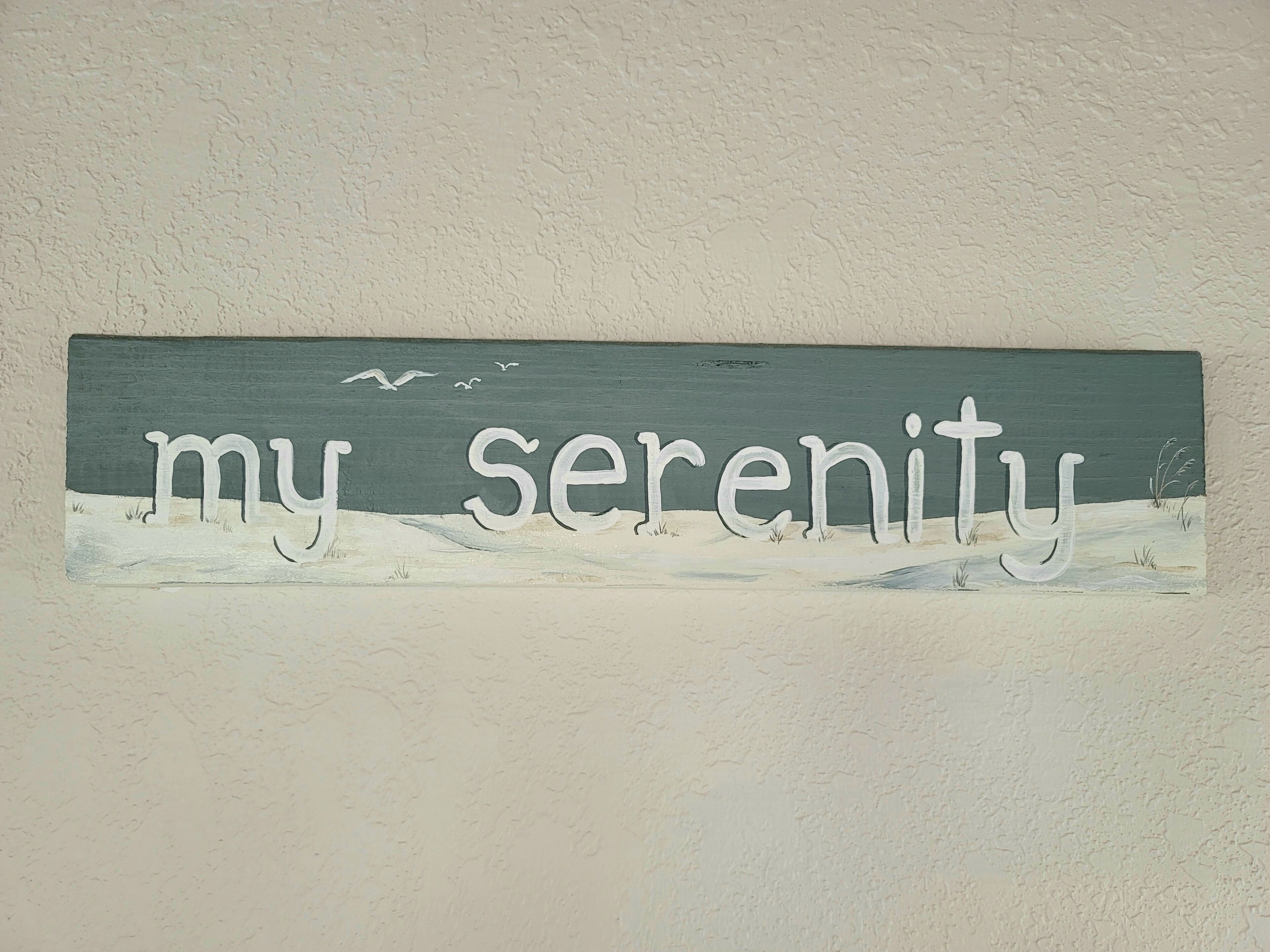 A wall with the text "my serenity" and a painting of a beach scene.
