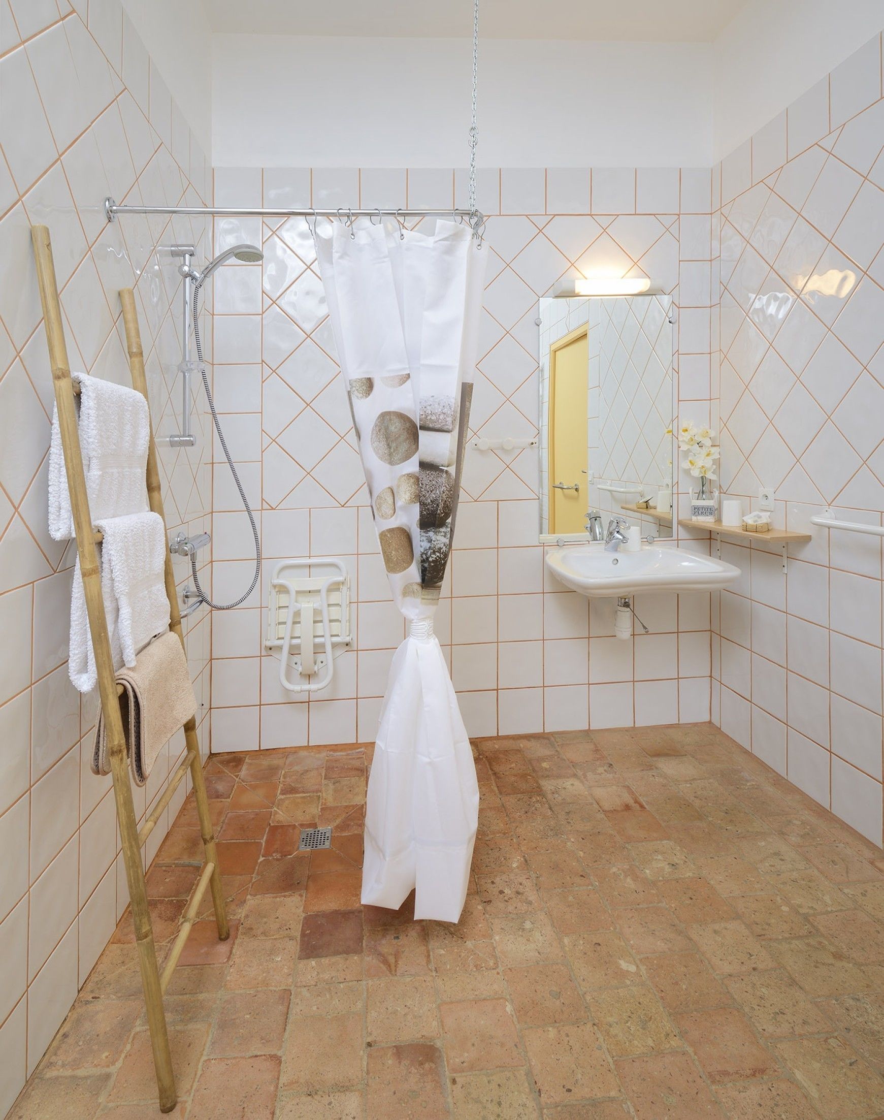 Un baño con ducha, lavabo, espejo y un perchero para toallas.