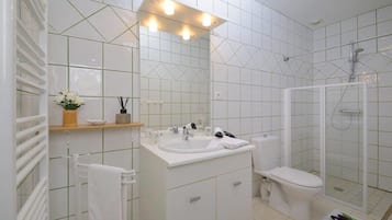 Ett modernt badrum med ett vitt handfat, en toalett och en dusch med glasväggar.