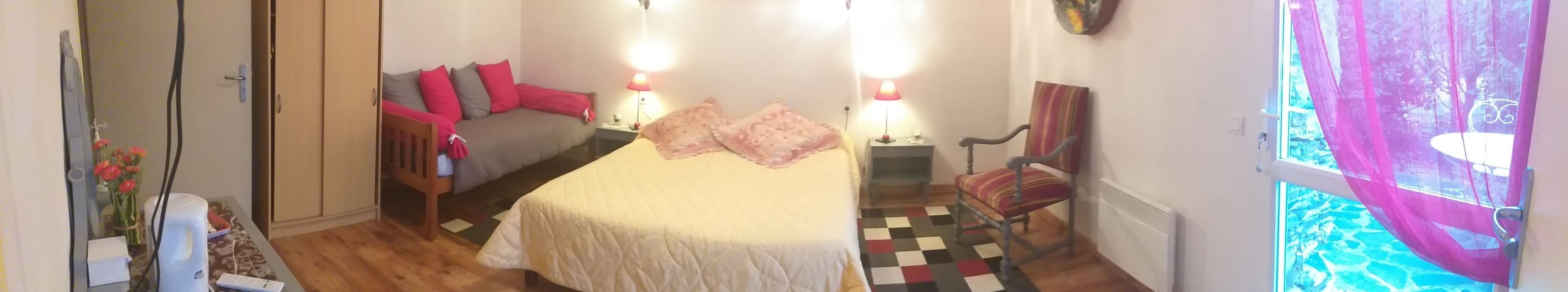 A bedroom with a bed, bedside tables, a chair, a window with a view, and a door.