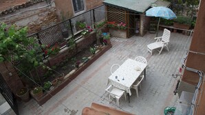 A courtyard with a table and chairs, a small garden with potted plants, and a blue umbrella. - Pretty House In Quiet And Traditional Neighborhood (Venezia)