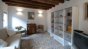 A living room with a sofa, a wooden cabinet, a bookshelf, and a television. - Pretty House In Quiet And Traditional Neighborhood (Venezia)