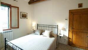 A bedroom with a bed, bedside lamps, a wooden door, a radiator, and a framed picture on the wall. - Pretty House In Quiet And Traditional Neighborhood (Venezia)