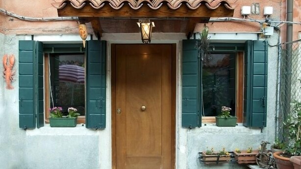 A wooden door with green shutters, a small porch area with potted plants, and a tiled roof. - Pretty House In Quiet And Traditional Neighborhood (Venezia)
