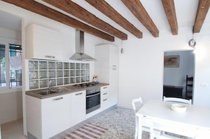A modern kitchen with white cabinets, a gas stove, and a stainless steel sink.