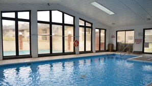 An indoor swimming pool with clear windows, a lifebuoy, and a no smoking sign.
