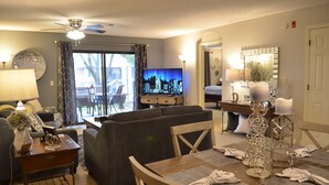 A living room with a sofa, TV, dining table, and chairs.