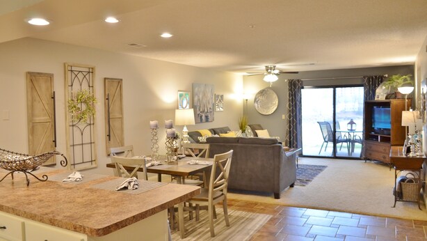A spacious living area with a dining table, chairs, a sofa, and a television.