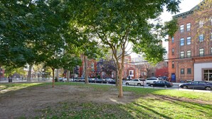 A park with trees and a street with parked cars and buildings. - 1 Bedroom Apt Hoboken  - Close to NYC/MetLife - FIFA (Hoboken)