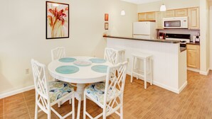 A dining area with a round table, white chairs, and a kitchen in the background. - 1 Bedroom Apt Hoboken  - Close to NYC/MetLife - FIFA (Hoboken)