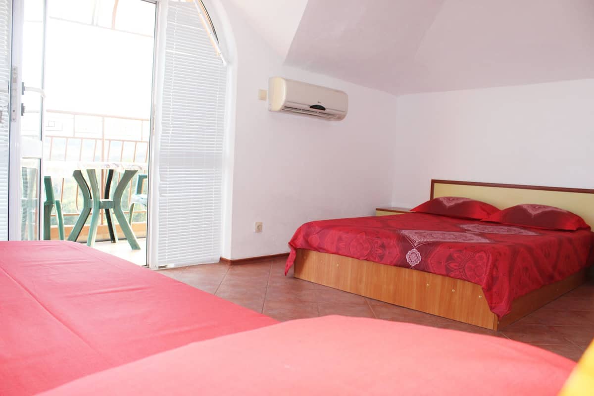 A bedroom with a bed, a window, and an air conditioning unit.