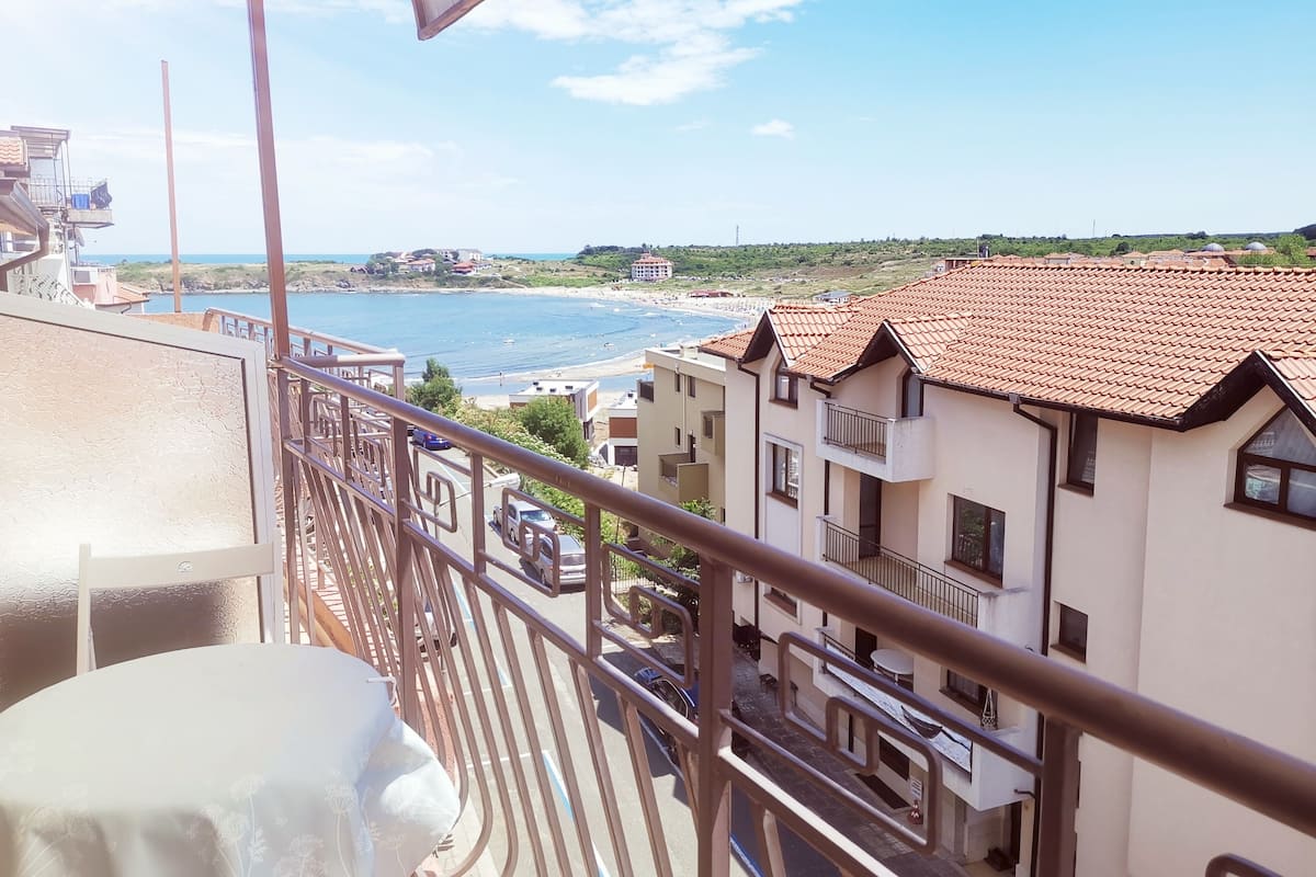 A balcony with a view of a beach and buildings.