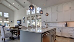 A spacious kitchen with white cabinetry, a large island, and pendant lighting.