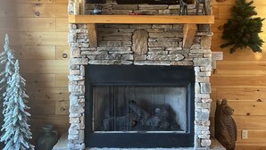 A stone fireplace with a flat-screen TV above it, surrounded by wooden walls.
